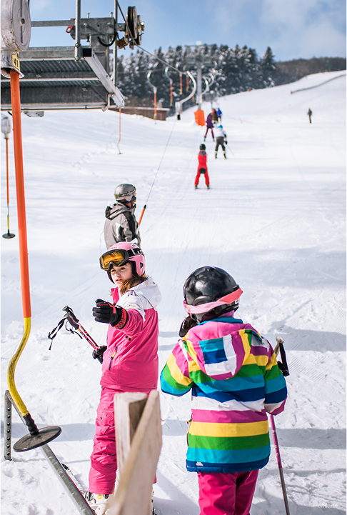 Des enfants en tenue colorée utilisent le téléski de l’école de glisse de Prabouré.