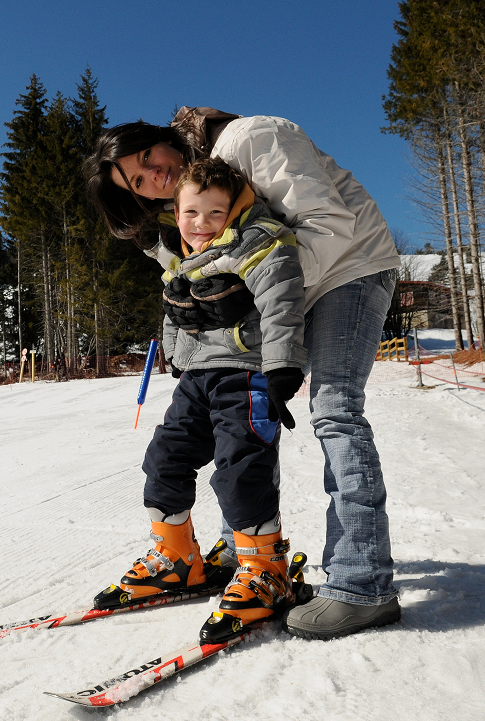 Une maman accompagne son enfant débutant sur des skis à l’école de ski de Prabouré.