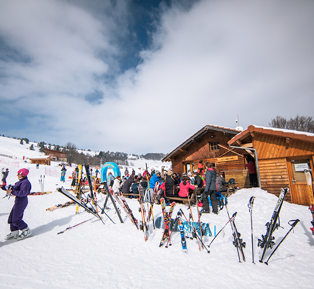 Chalet en bois et skieurs en pause à la station de Prabouré sous un ciel d’hiver.